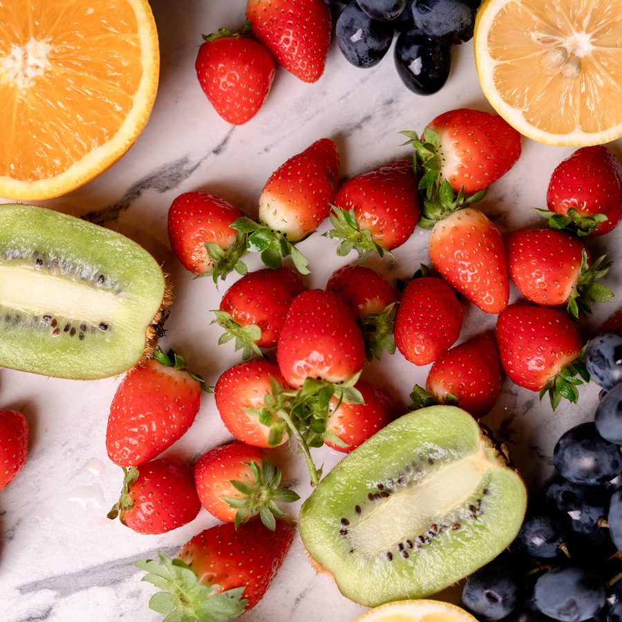 Strawberries, citrus, kiwi and grapes on marble